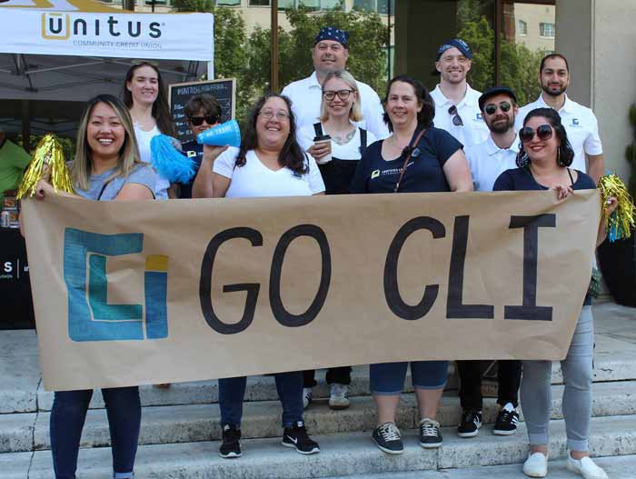 Eleven CLI teammates stand behind a handmade sign that says go CLI at a company team building outing.
