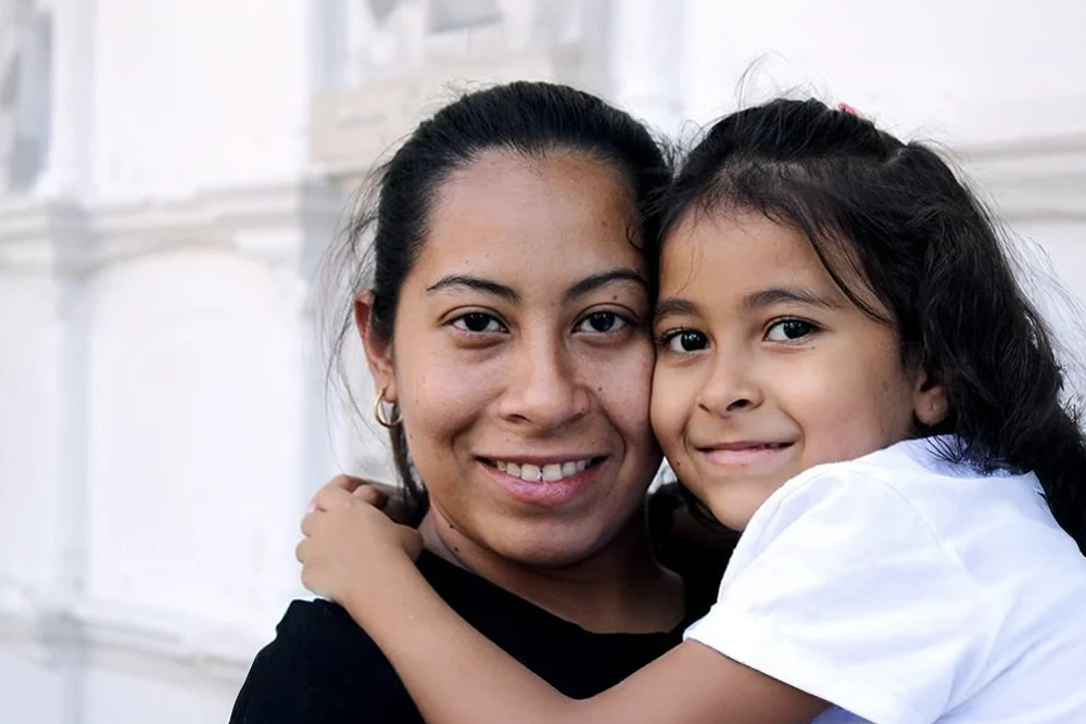 A loving mother holds her child after communicating with a doctor in their preferred language.