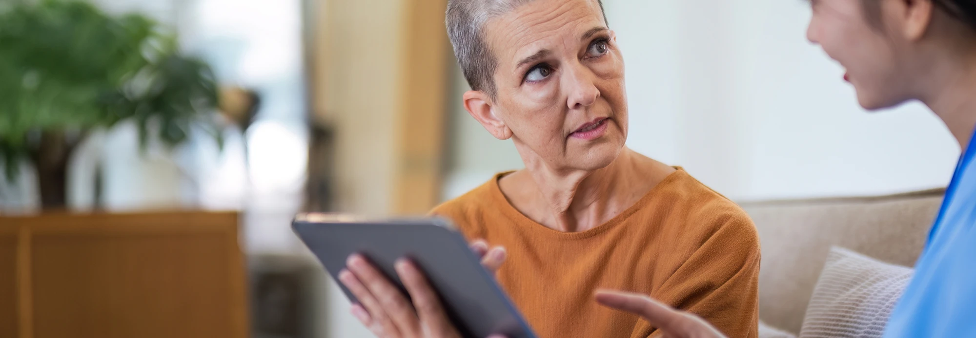 A patient and a medical provider discuss treatment plan information presented on a tablet.