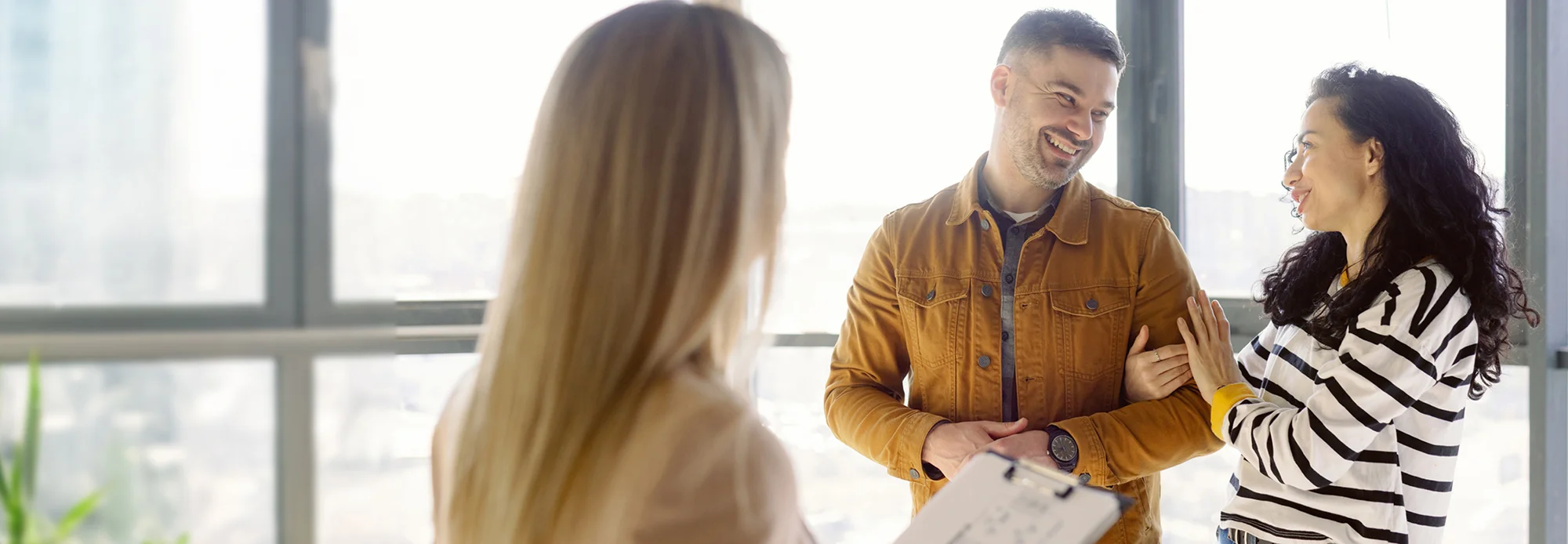 New homeowners smile at each other after talking with a mortgage professional and an interpreter.